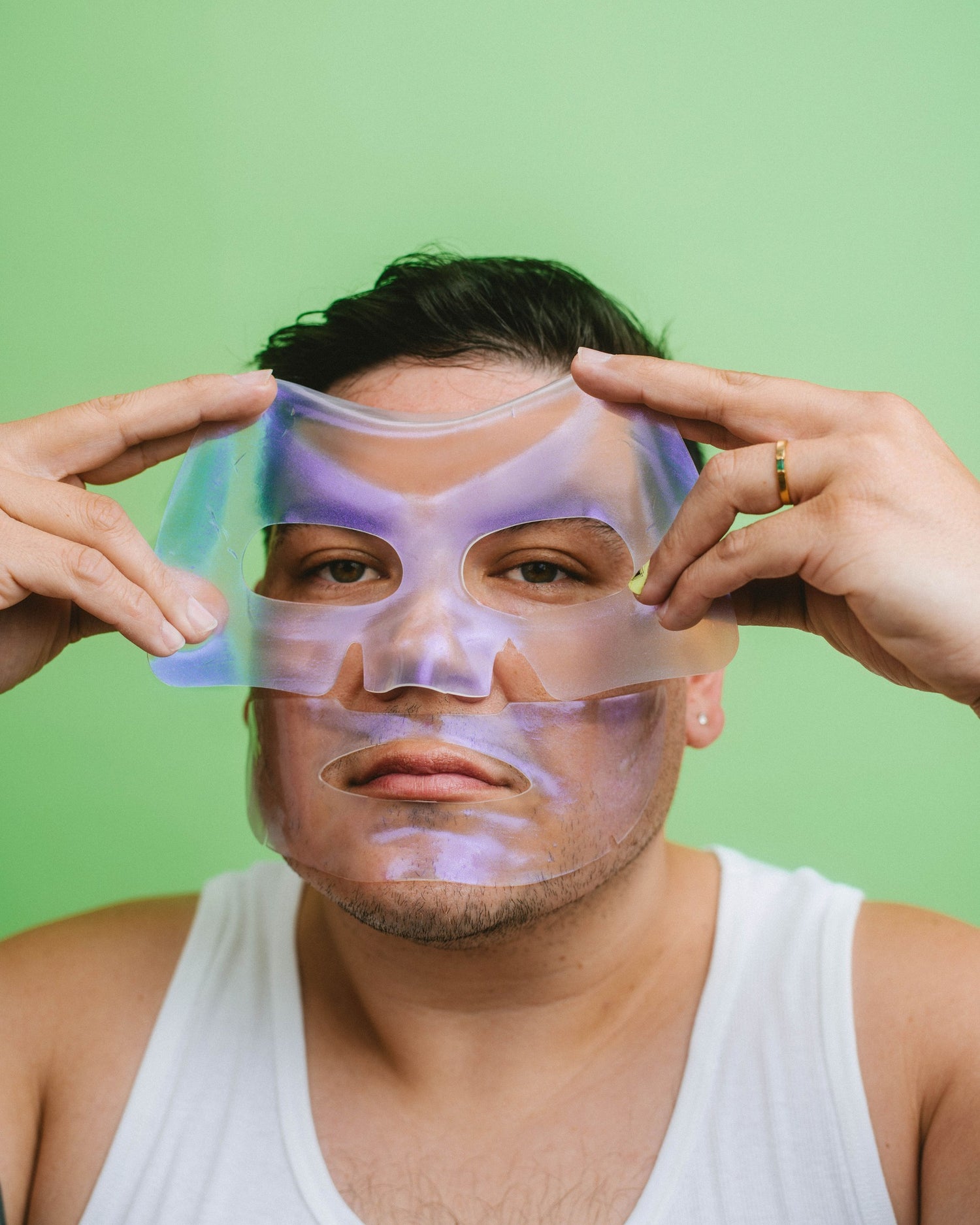 Person applying iridescent aura mask to face